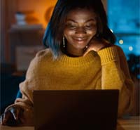 A woman engaging in online tarot reading, illuminated by blue and warm lights, practicing spiritual tarot skills for intuitive insights and self-discovery.