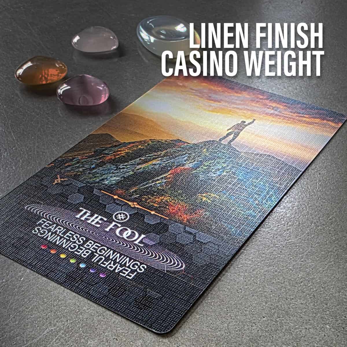 Vibrant tarot card titled "The Fool" with a landscape background and spiritual symbols, accompanied by colorful gemstone crystals on a dark surface, conveying intuitive and spiritual tarot guidance.